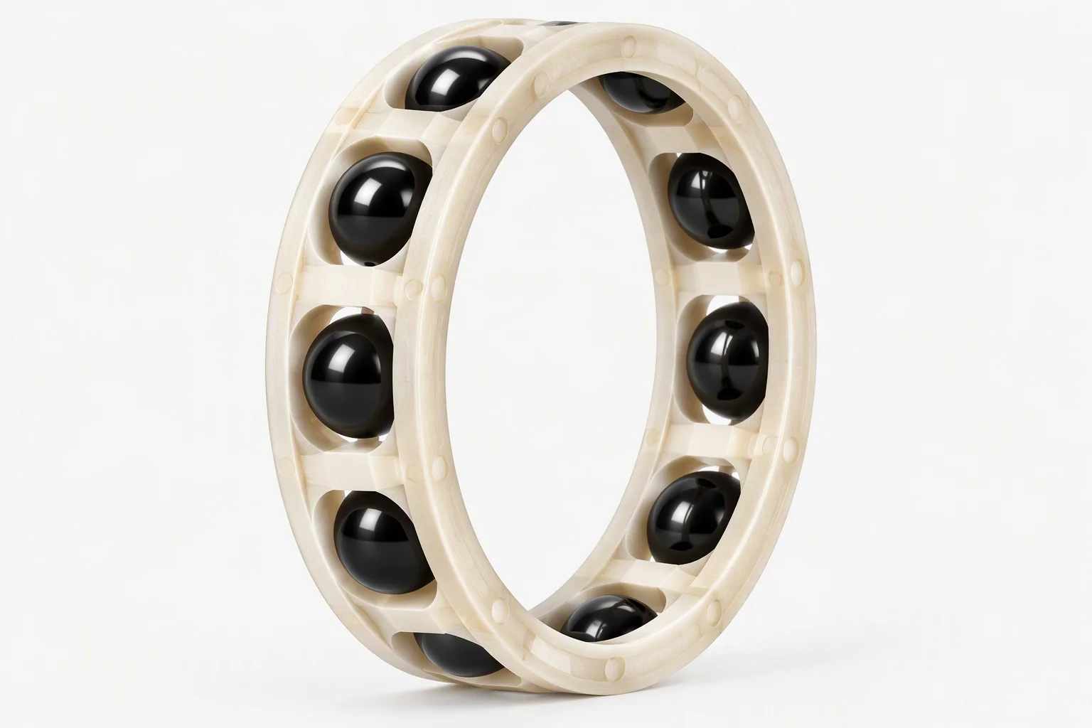 A cream-coloured machined cage ring holding a circle of polished black balls, photographed standing on edge